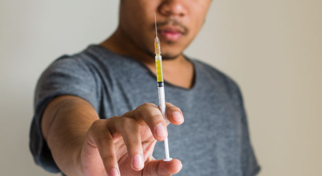 manholding a needle filled with heroin